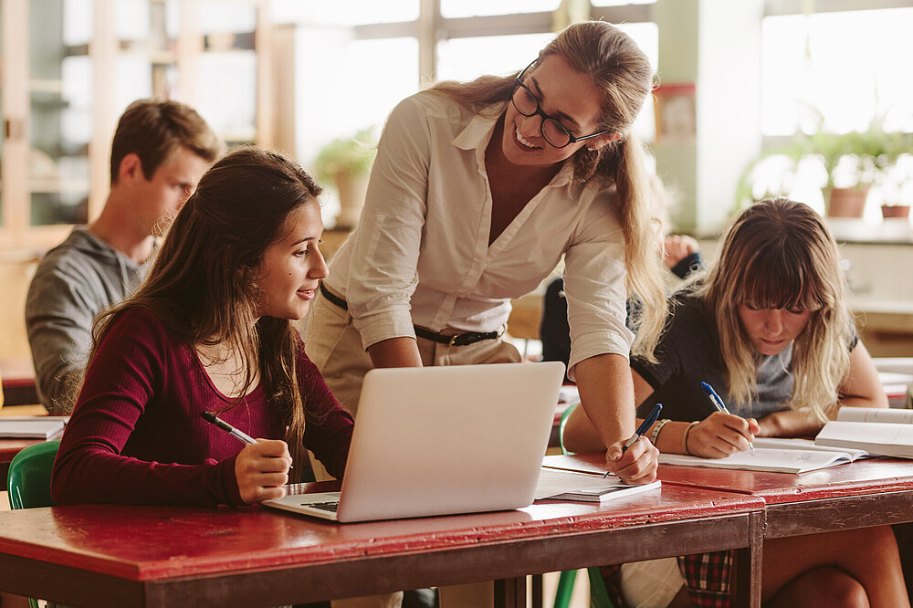 Lehrerin im Unterricht bei Schülerin mit Laptop