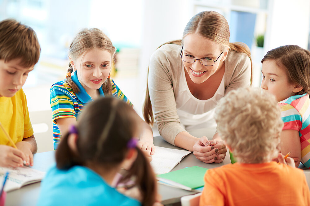 © iStockphoto.com Lehrerin mit Schülern bei Gruppenarbeit im Gespräch